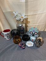 Photo showing the entire collection of skulls, pumpkin candles, cauldron, vase with skull floral design, and artificial flowers.