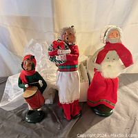 Front view of three Byer's Christmas Carolers figurines on display, showing detailed clothing and facial expressions.