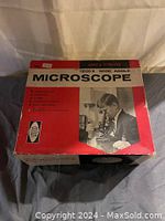 Box front of the microscope, showing 1200X wide angle text and image of a person using the microscope.