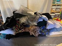 Pile of assorted women's plus size clothing including tops, pants, leggings, and bathing suits in various colors and patterns.