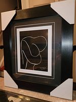 Framed Henri Matisse print with protective corner guards on a black frame with white matting.