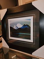 Overall view of framed mountain landscape print with protective corner covers on frame, showing the full artwork and frame.
