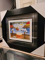 Front angle of professionally framed Maud Lewis print showing vibrant colors and part of the frame and protective corners.