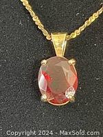 Close-up of red oval stone in 14 kt gold prong setting pendant