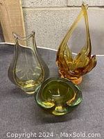 Two Murano glass sculptures, one yellow etched and one orange, with green ashtray in front