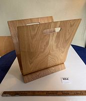 View of the bentwood interlocking wooden magazine rack showing its two interlocking curved panels with carry handles and base.