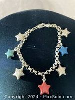 Full view of the bracelet showing five multi-colored star charms including blue, white, and cream colors on a silver chain.