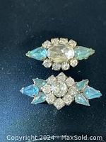 Two vintage 1960s glass brooches with clear and baby blue glass stones, detailed photo showing stone arrangement and condition.