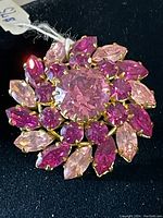 Top view of the brooch showing the pink rhinestones arranged in floral pattern on gold-tone metal base.