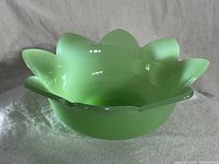 Top and angled views of the pale green antique glass bowl shaped like a lotus flower, showing the scalloped petal edges and rounded base.