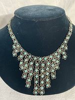 Front view of the full ornate choker necklace showing the turquoise beads and fringe design on a black display.