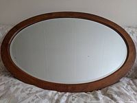 Full view of the large oval mirror showing wooden frame and overall shape.