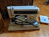 Machine on its base with power cord and stitch selector knobs visible