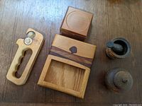 Top view of kitchen accessories arranged on wooden surface showing ceramic mortar and pestle, wooden coasters, napkin holder, and sharpener.