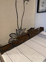 Full side view of expandable wooden Eastlake window accent, showing length and carved details along the front.