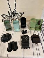 Full view of all 9 antique match boxes and cast iron holders arranged on fabric with floral pattern background