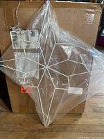 Metal diamond-shaped star wrapped in clear plastic, showing new condition and packaging.
