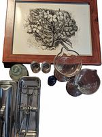 Overview photo showing framed floral art, cobalt blue bottle, various glass beakers and jars, and metal medical tools in a tray.