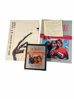 Clear top-down view of Atari E.T. cartridge with two manuals including a tips booklet showing E.T. hand and title text.