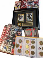 Framed Ryan Getzlaf hockey card with pin, multiple hockey cards in plastic sleeves, and 1998 Team Canada coin medallion set.