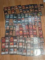 Overall layout of a large collection of Magic: The Gathering cards spread out on a floor, showing red, blue, black, and some green cards.