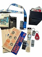 Photo showing wristwatch, keychains, Wicked Bluetooth headphones in packaging, lighter, PNE brochures, and Toronto Blue Jays lanyard