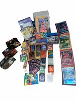 Full lot overview showing assorted Pokemon cards, deck sleeves, empty tins, and pins arranged on a white background.