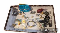 Overview of assorted small items including pins, figurines, small purse, rings, and decorative box