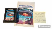 Space Invaders Atari cartridge with original manual and a handwritten note describing the item and price.