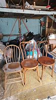 Three vintage wooden chairs side by side showing the style and condition, including scratches and wear. The leftmost chair is different in style and color from the two bentwood chairs on the right.