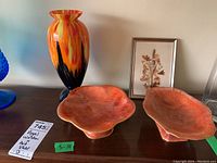 Photo showing the tall orange and black glass vase, two orange Royal Winton stemmed bowls, and framed pressed flower art in background