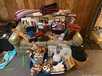 Wide view of the craft supply lot arranged on and around a floral armchair including yarn, books, blankets, faux flowers, and craft tools.
