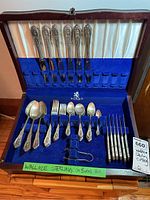 Front view of open Birks wood case with blue velvet lining showing forks, spoons and tongs