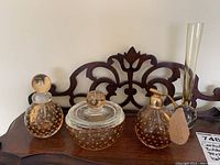 Four controlled bubble glass pieces including perfume bottle, atomizer, bowl, and vase as seen on a wooden surface.