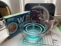 Photo showing nested blue glass mixing bowls, clear glass measuring cup, Muffin Mania cupcake pan, and boxed Weight Watchers electronic food scale.