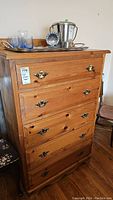 Front view of pine dresser showing five drawers with brass handles and natural wood finish.