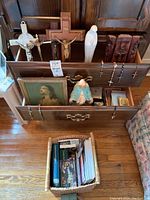 Photo showing multiple wooden crucifixes with crucifixes, religious figurines, framed print and religious necklaces neatly arranged in drawers and on shelves.