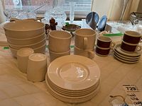 Wide view of Royal Doulton Mercury White dinnerware assortment showing mugs, plates, bowls and salt and pepper shakers arranged on table.