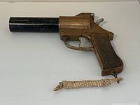 Side view of brass flare pistol on white background