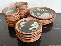 Full lot view showing stacks of dinner plates, side plates and bowls on black surface against white background.
