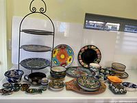 Full view of lot on table including wrought iron stand and all pottery pieces