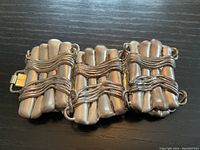 Close-up of the bracelet laid flat showing the three large linked silver pieces with wire wrapping detail and clasp.