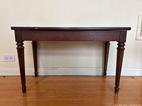 Front view of dark wood piano bench, showing rectangular seat and turned legs