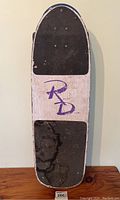 Top view of the skateboard showing the grip tape on nose and tail with middle section featuring the Roller Derby logo and signs of wear and discoloration.