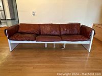 Front view of full sofa showing white painted plywood frame and four cognac leather cushions