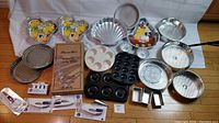 Photo of assorted pans and kitchen tools including Tinkerbell pans, scalloped pie tins, donut pans, and more.