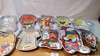 Full view of all 10 collectible character cake pans arranged on a table showing colorful laminated character inserts and shapes