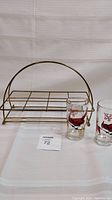 Two Cardinal glasses and brass glass holder arranged on cloth background.