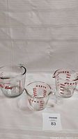Three vintage glass measuring cups set on white background, from left Fire-King 1 L cup and two Pyrex cups smaller sizes