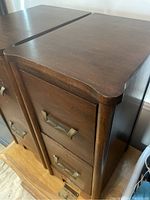Close-up photo showing the top surface, front and brass drawer handles of the antique wooden night stand.